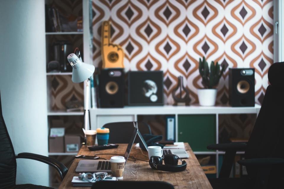 A tidy desk flatlay with a small green plant, headphones and a notebook