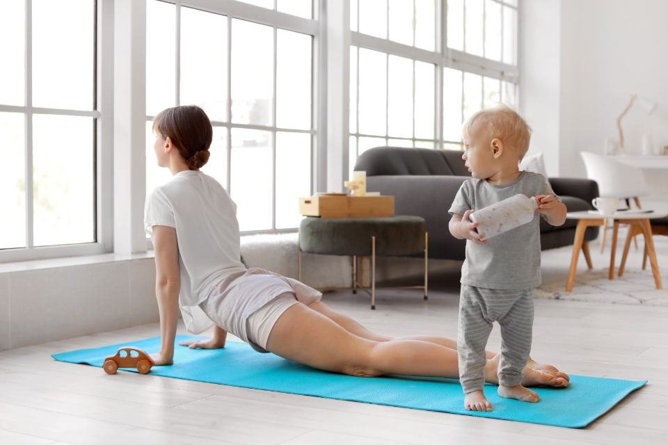 A person stretching on a mat in a bright room at home