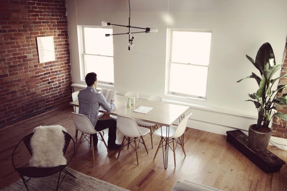 A person working at a dining table on a hard dining chair