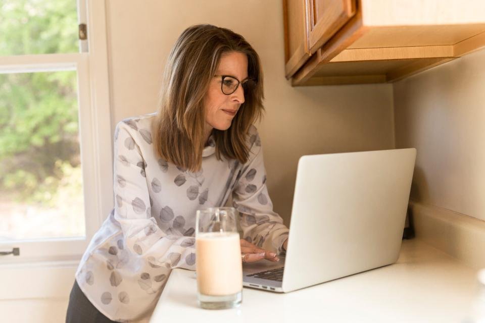 A person working on a laptop at a bright kitchen counter