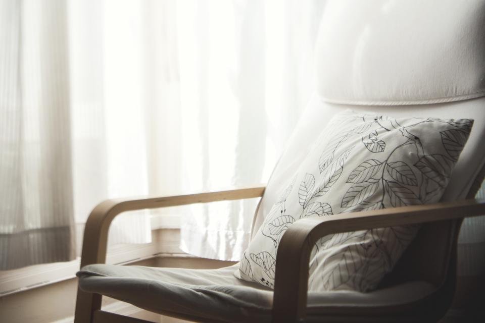 A soft-furnished corner with an upholstered armchair and sheer curtains